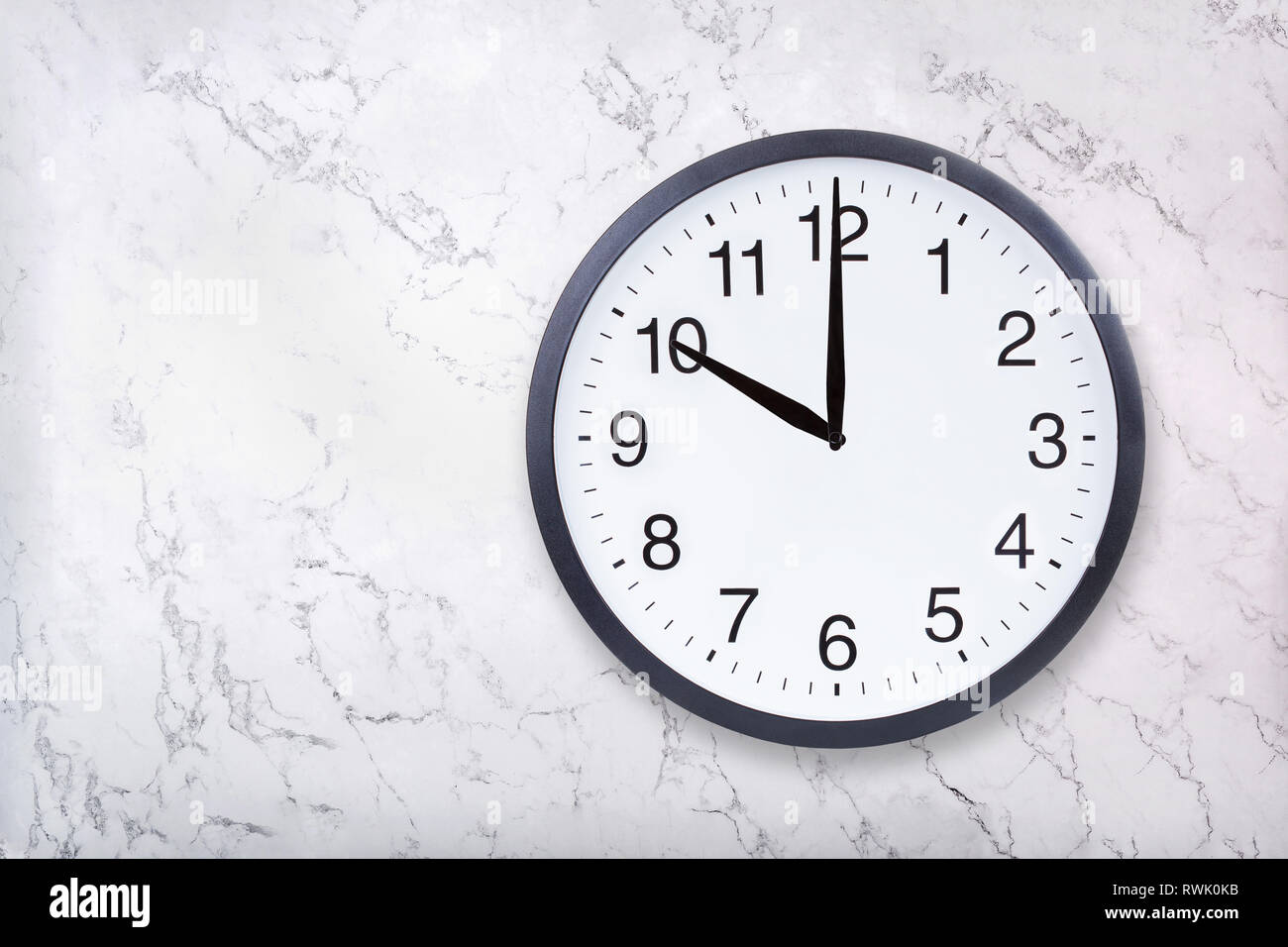 Wall clock show ten o'clock on white marble texture. Office clock show 10pm or 10am Stock Photo
