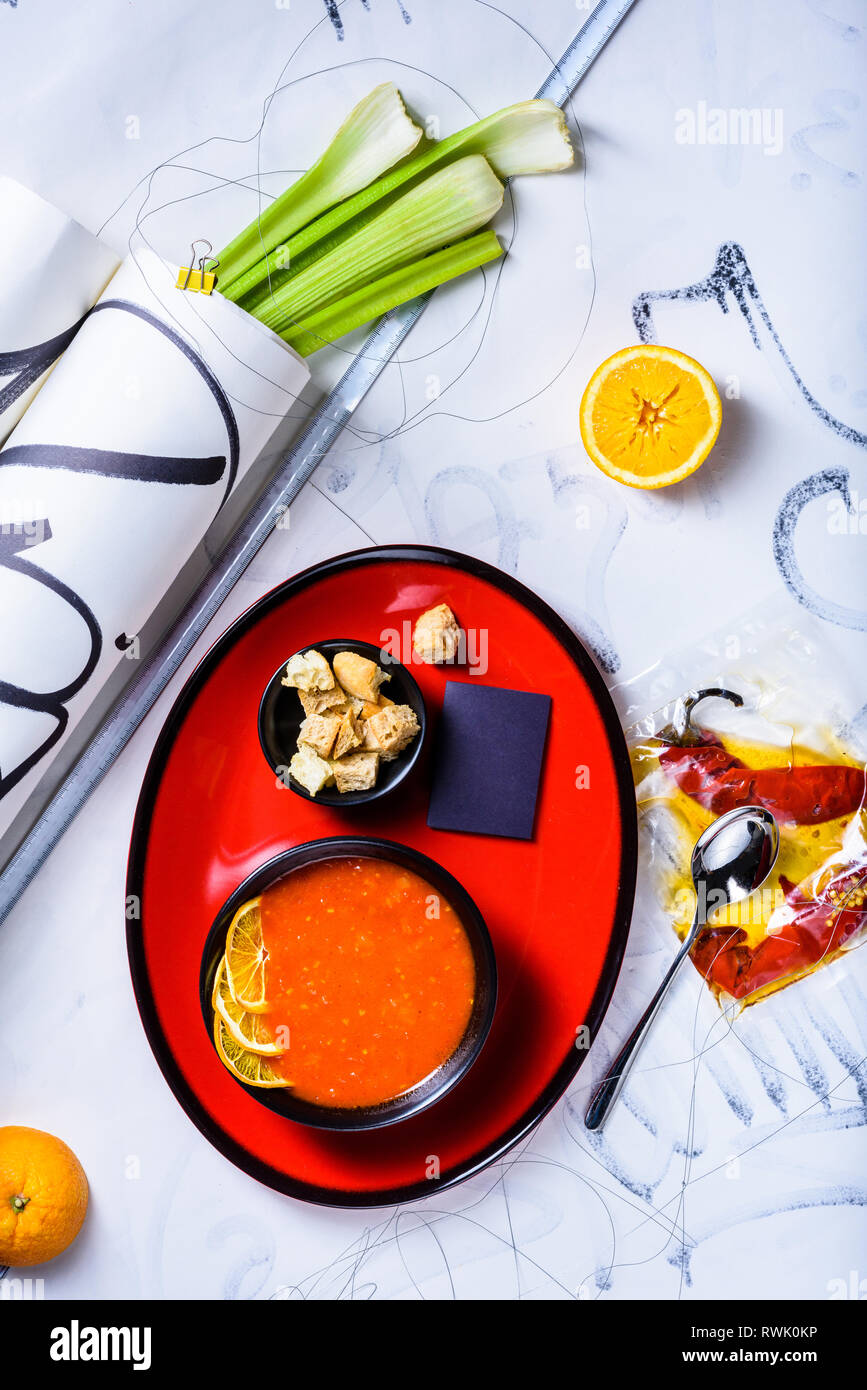 Tomato soup with croutons and cooking ingredients, served in a bowl on white background. View from above, flat lay. Stock Photo