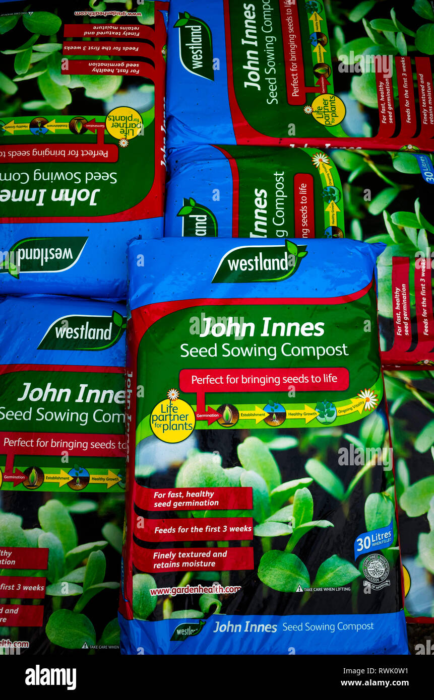 A stack of bags of John Innes seed sowing Compost in a garden centre labelled Perfect for bringing seeds to life Stock Photo