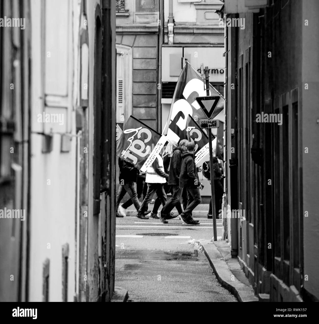 Strasbourg, France - Sep 12, 2017: View through tiny street at crowd with flags - political march during a French Nationwide day of protest against the labor reform proposed by President Macron - black and white Stock Photo