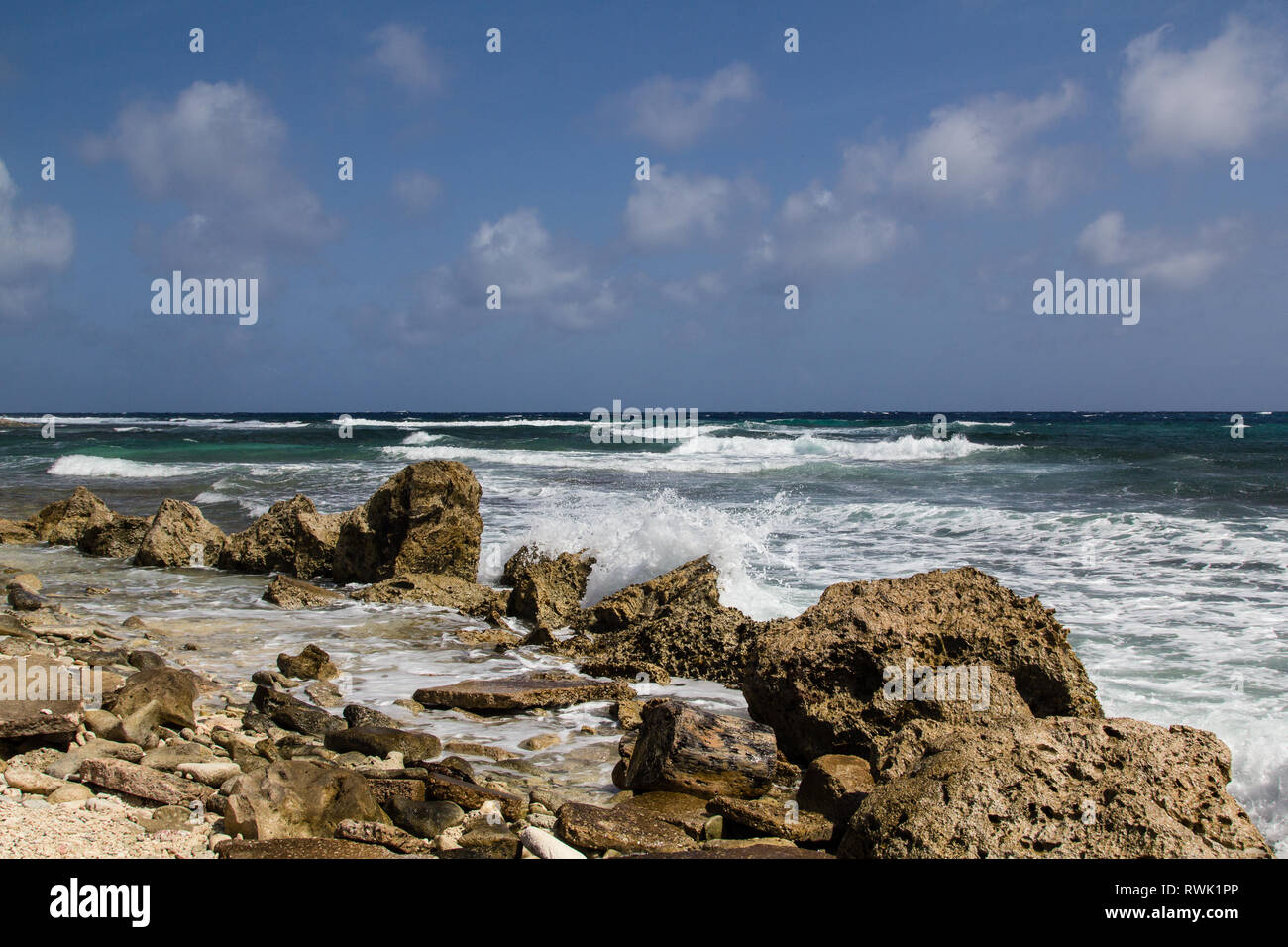 Wild and high waves rooling in at the rough and rocky shoreline of the east coast of the island of Bonaire in the caribbean Stock Photo