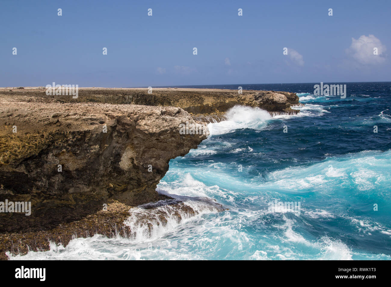 Wild and high waves crashing at the rough cliffs of the east coast of the tropical island Bonaire Stock Photo