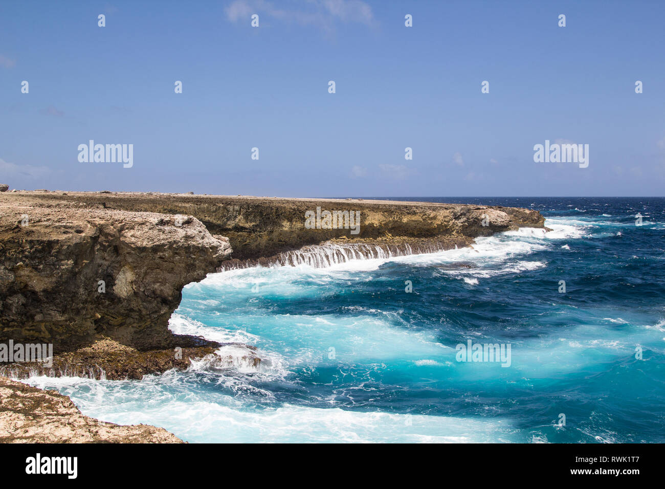 Wild and high waves breaking at the rough vulcanic rocks of the east coast of the tropical island of Bonaire Stock Photo
