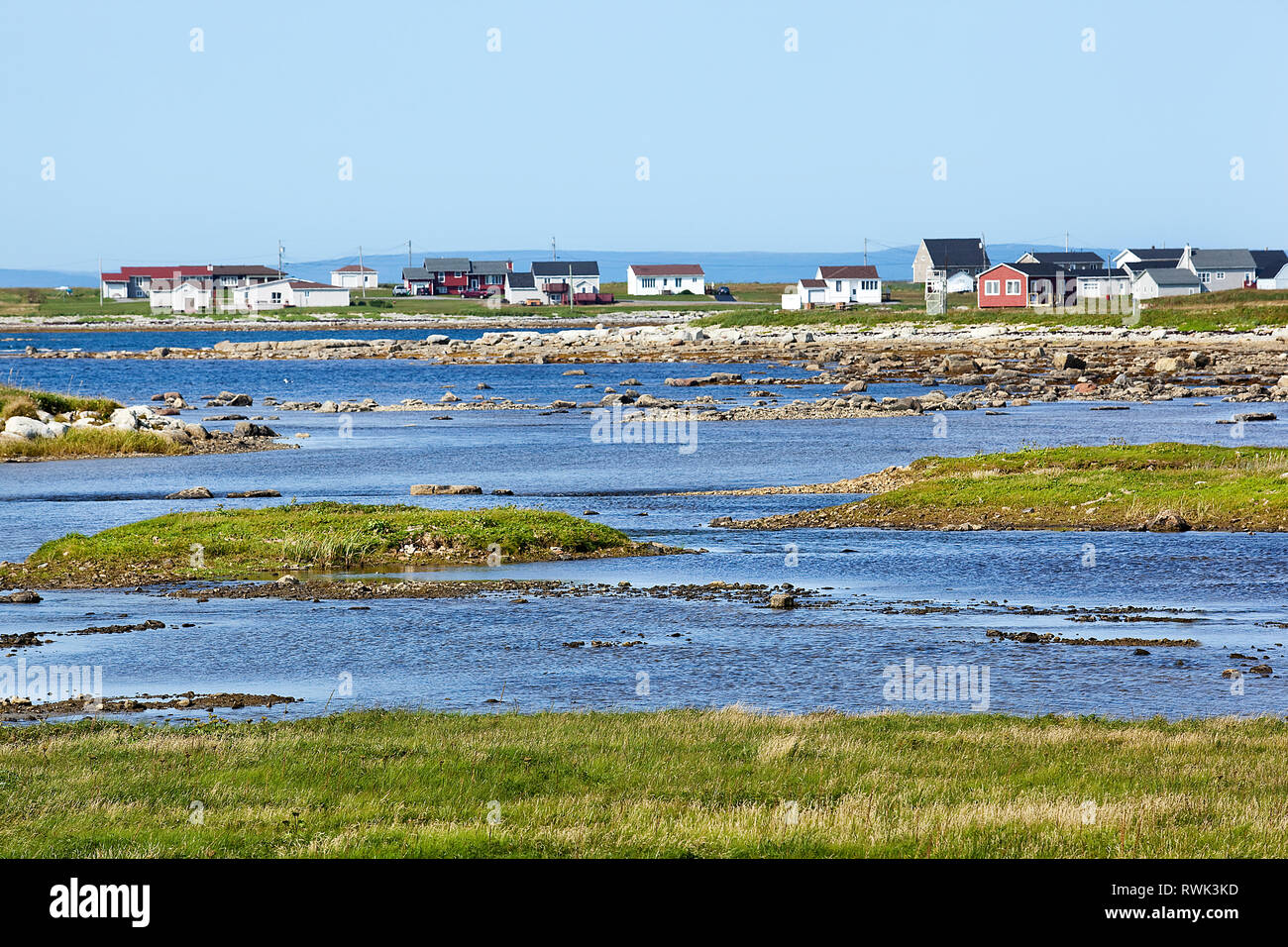 Low-lying tidal area beyond which is the small costal town of Flower's Cove, Western Newfoundland, Canada Stock Photo