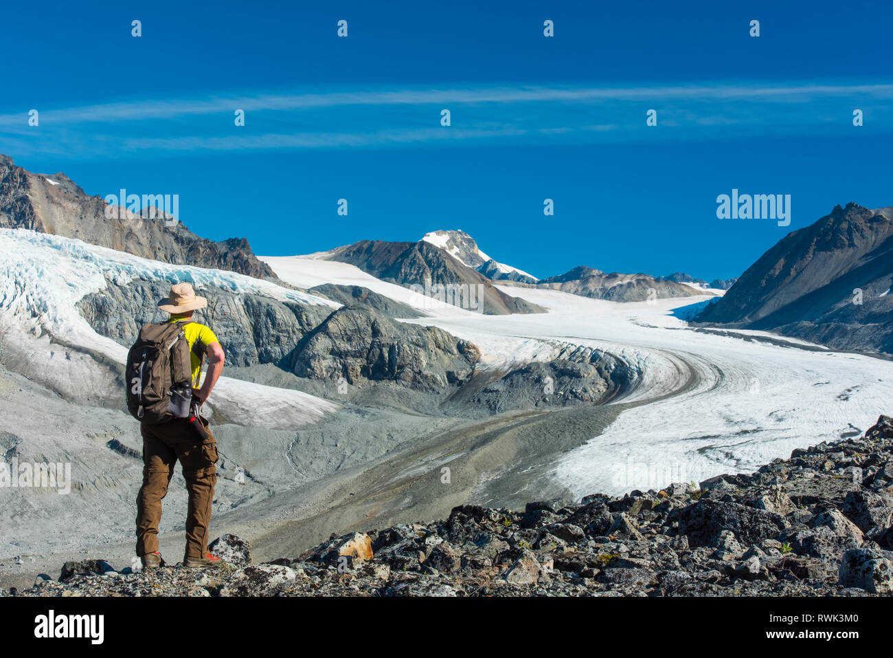 A man walks in Gulkana Glacier Valley in the Eastern Alaska Range in South-central Alaska on a sunny summer afternoon Stock Photo