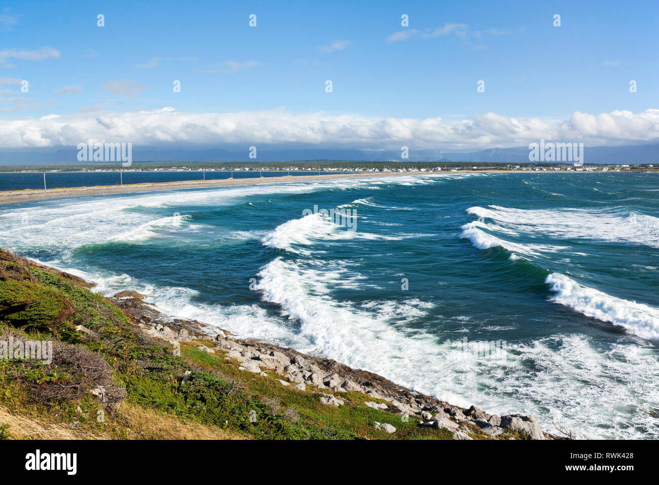 Shallow Bay in Cow Head is characterized by near-constant wave action abuting a 2,5 km isthmus that links the town (in the background) to the Cow Head Peninsula (from where the photo was taken), Western Newfoundland, Canada Stock Photo