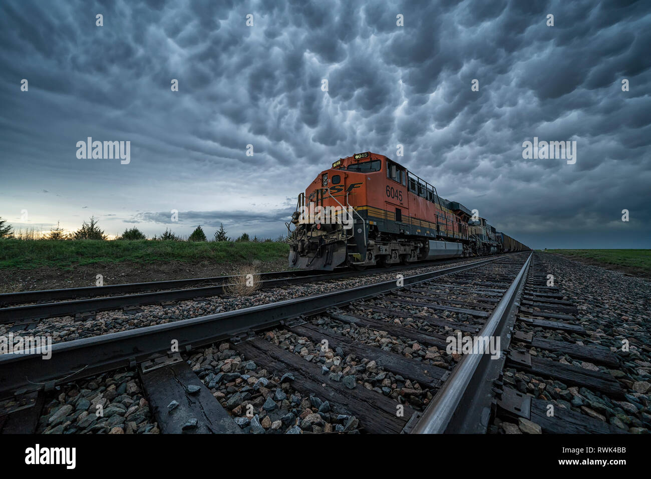 Freight train with mammatus clouds overhead while on a storm chasing tour; Oklahoma, United States of America Stock Photo