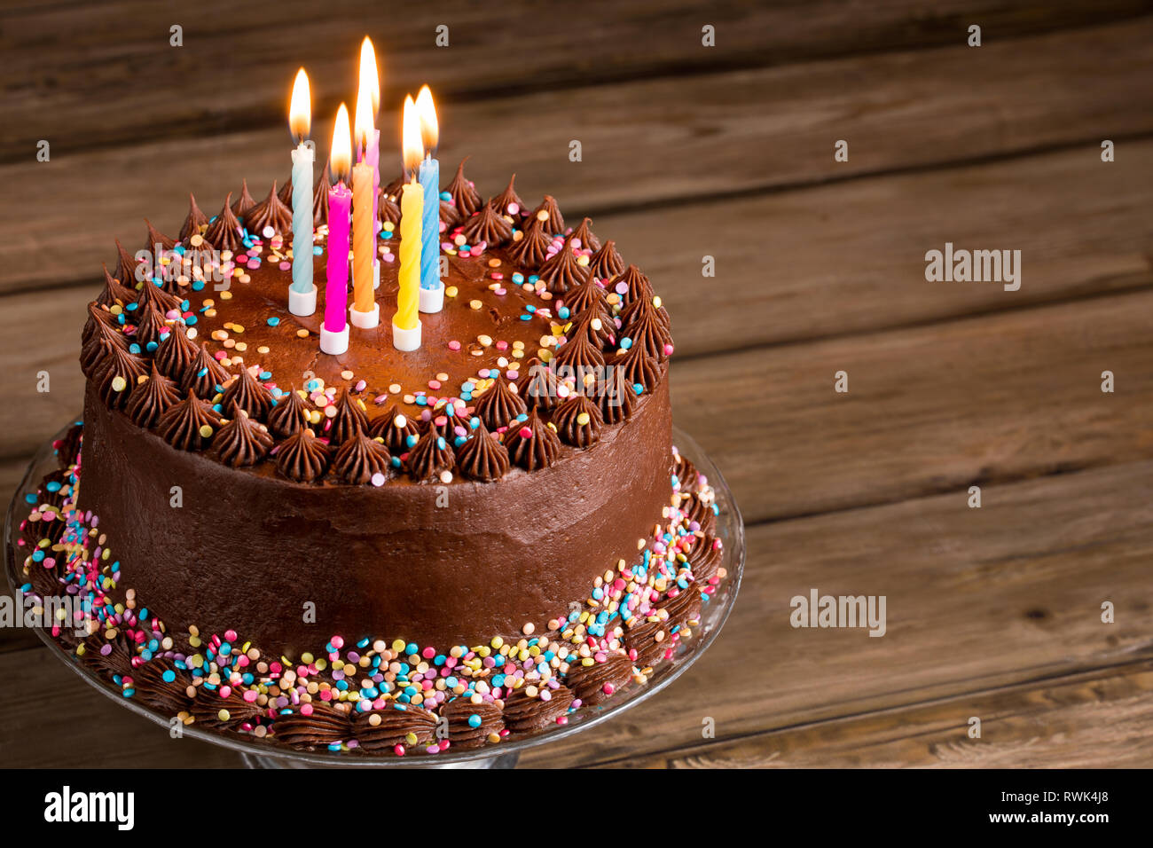 Chocolate birthday cake with colorful sprinkles and candles over ...