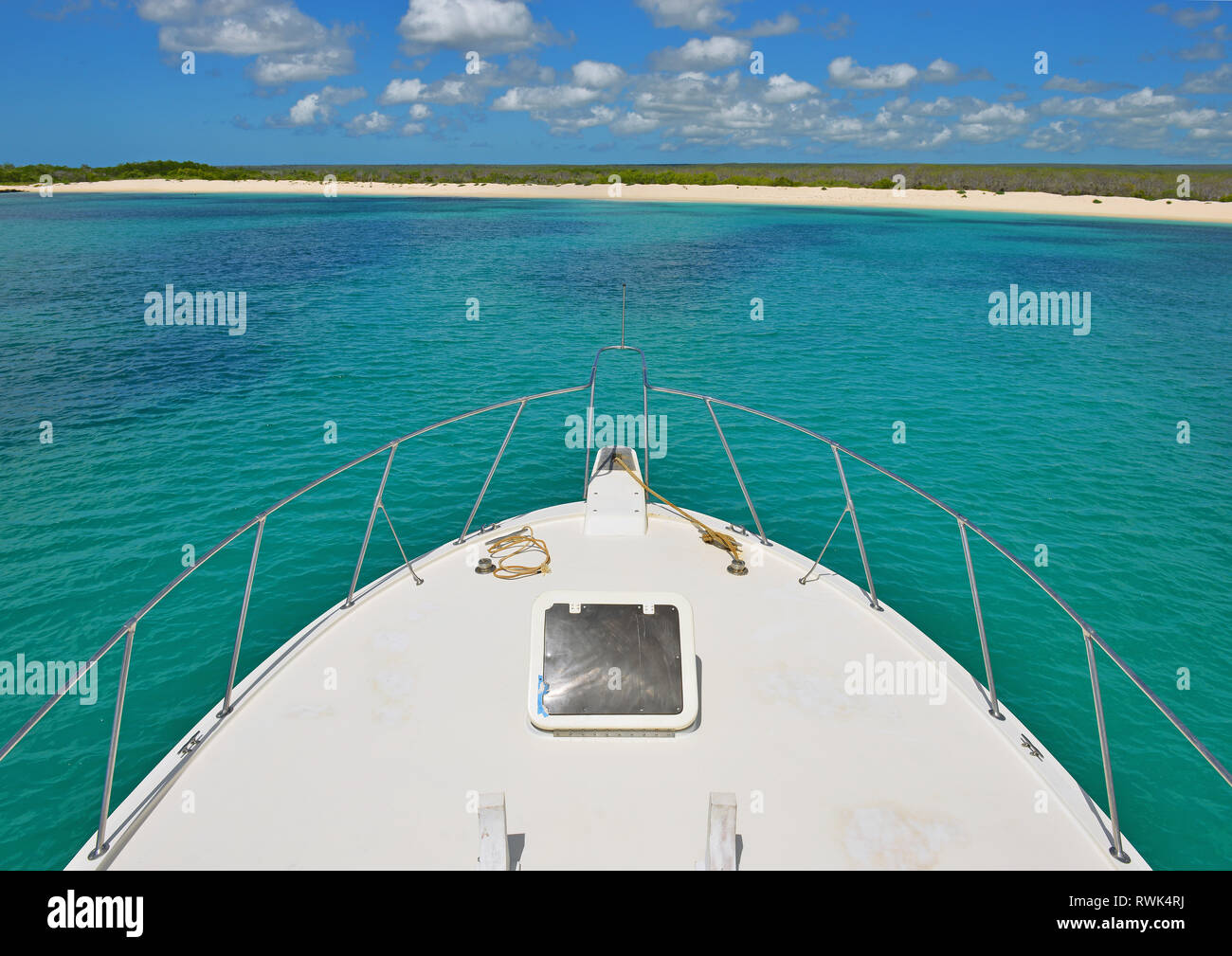 The front of a yacht cruising in the Galapagos islands national park with the beach of South Plaza Island in the background, Pacific Ocean, Ecuador. Stock Photo