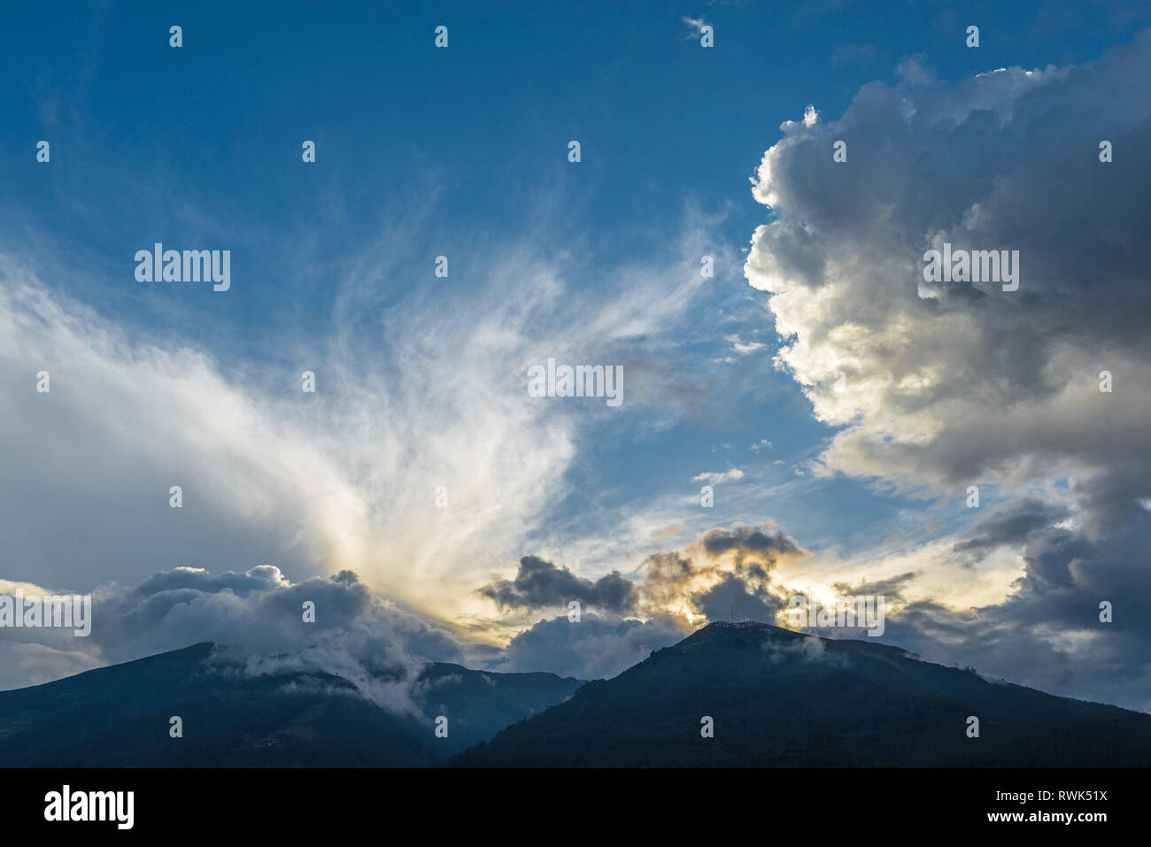 Cloudscape with the peaks of the Pichincha volcano at sunset seen from the city of Quito in the Andes mountain range, Ecuador, South America. Stock Photo