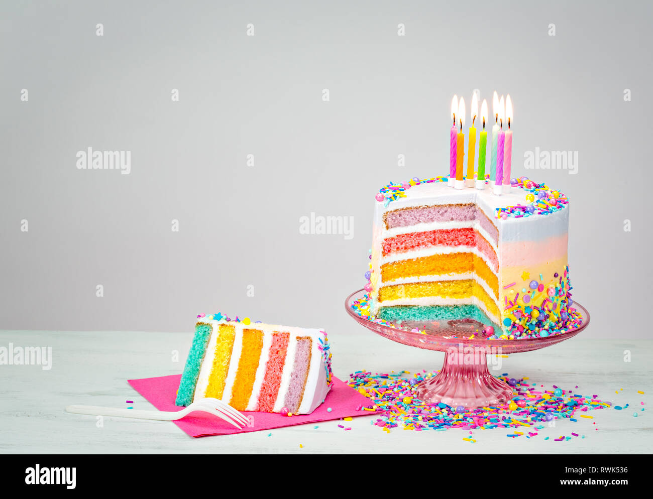 Colorful rainbow layered Birthday cake with lit candles and sprinkles ...
