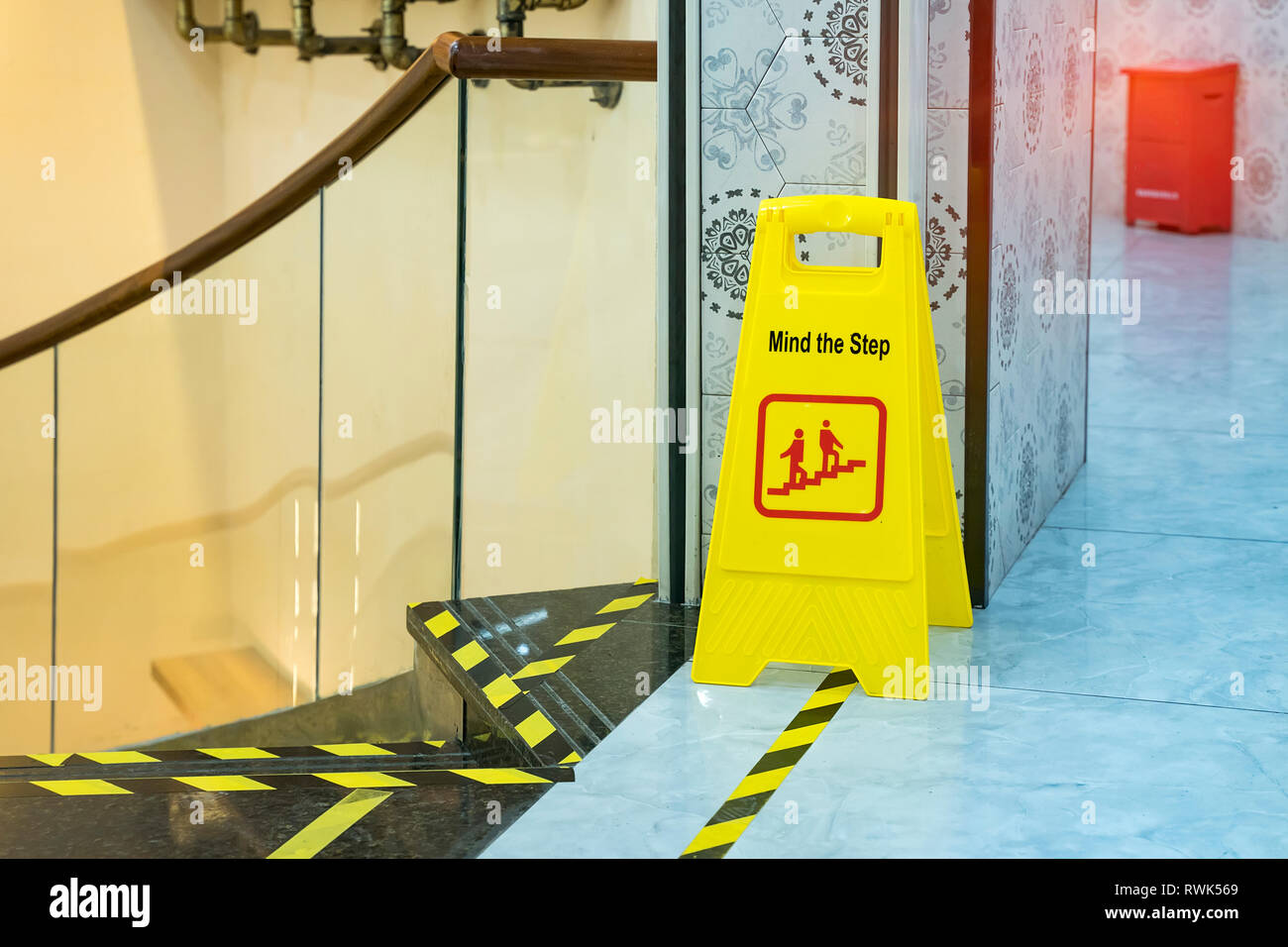 Yellow caution warning sign mind the step on wooden floor at staircase. Stock Photo