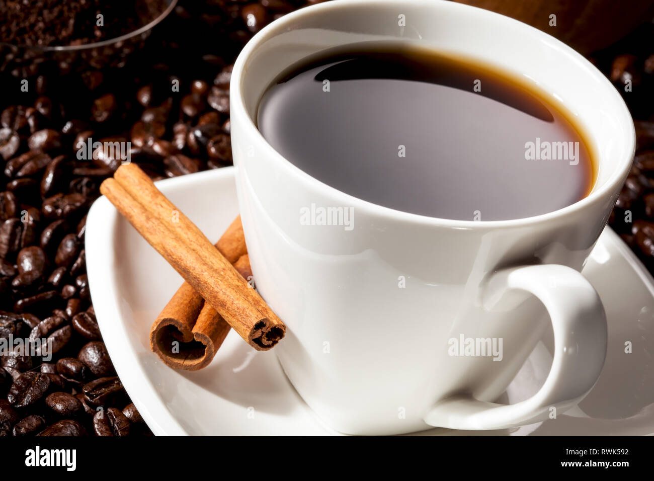 Close-up of Black Coffee in a white Coffee cup with cinnamon and whole beans. Stock Photo