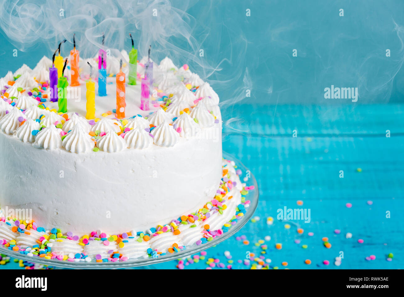 White Buttercream icing birthday cake with blown out Candles over blue background Stock Photo