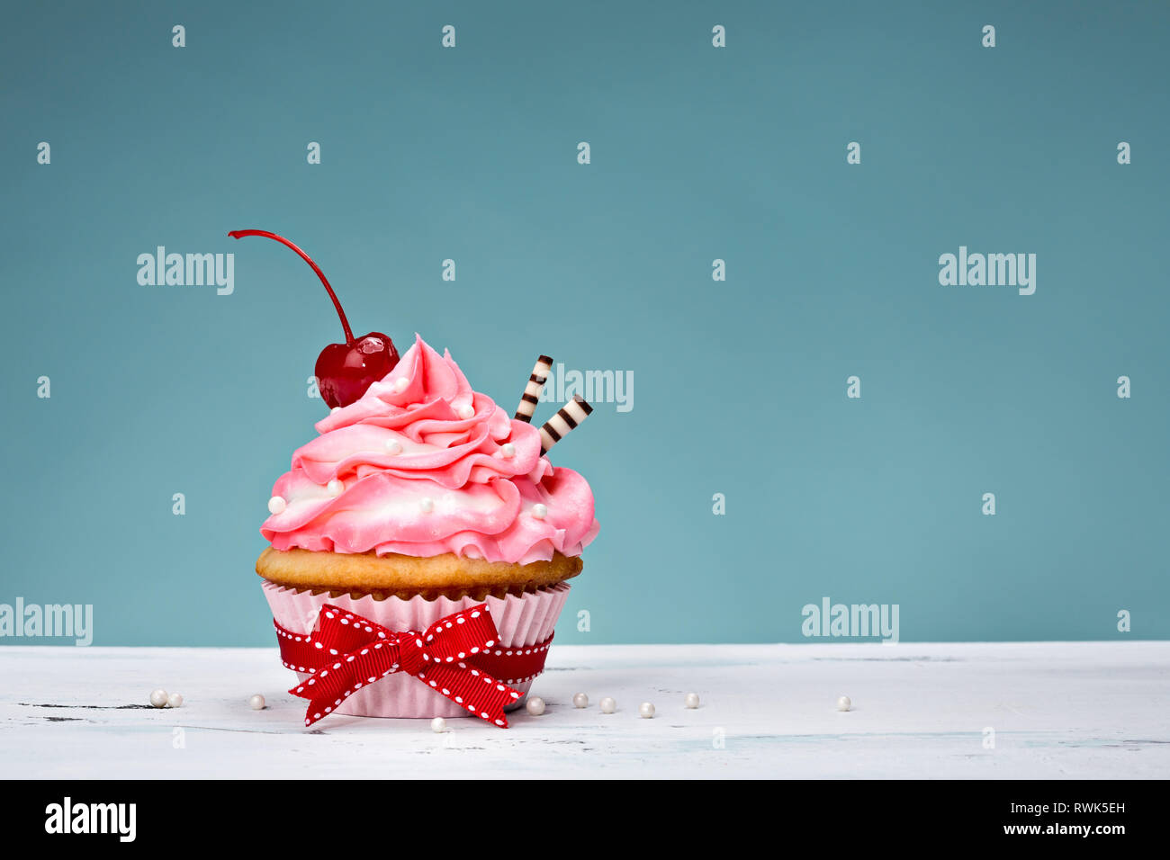 Cupcake with pink buttercream icing and a cherry on top Stock Photo - Alamy