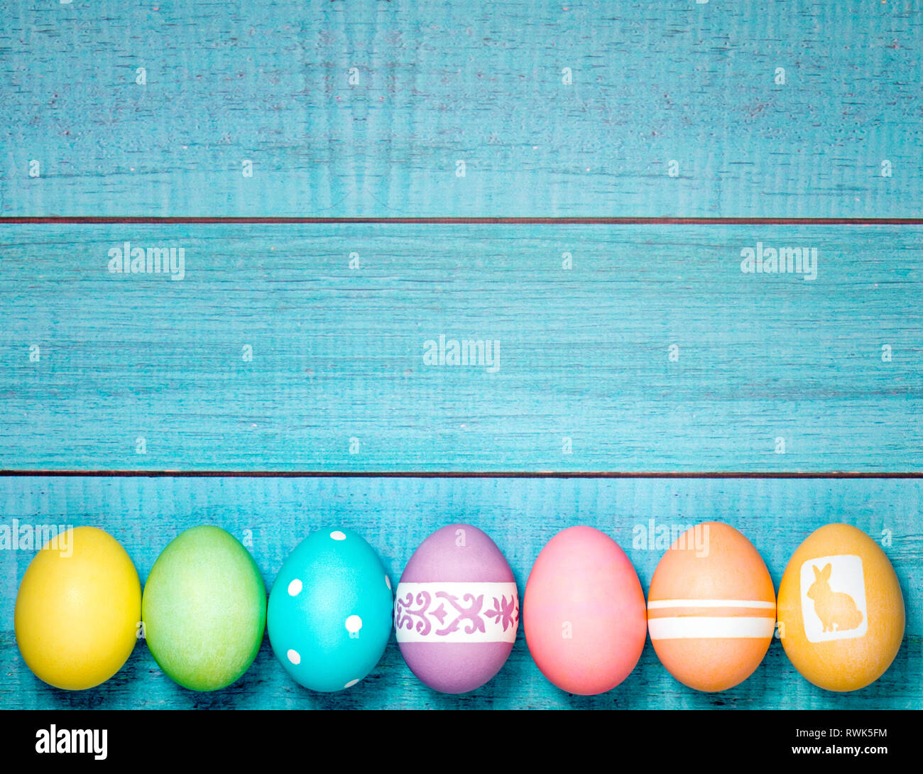 Colorful Easter Eggs arranged in a row on a blue background. Stock Photo