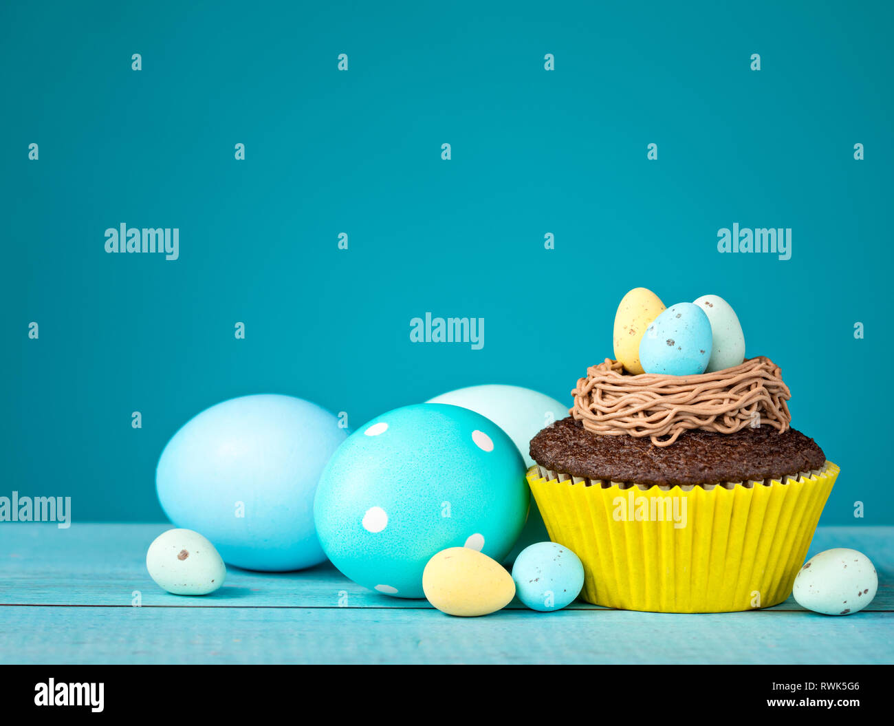 decorated Easter eggs and cupcake with Candy on a blue background. Stock Photo