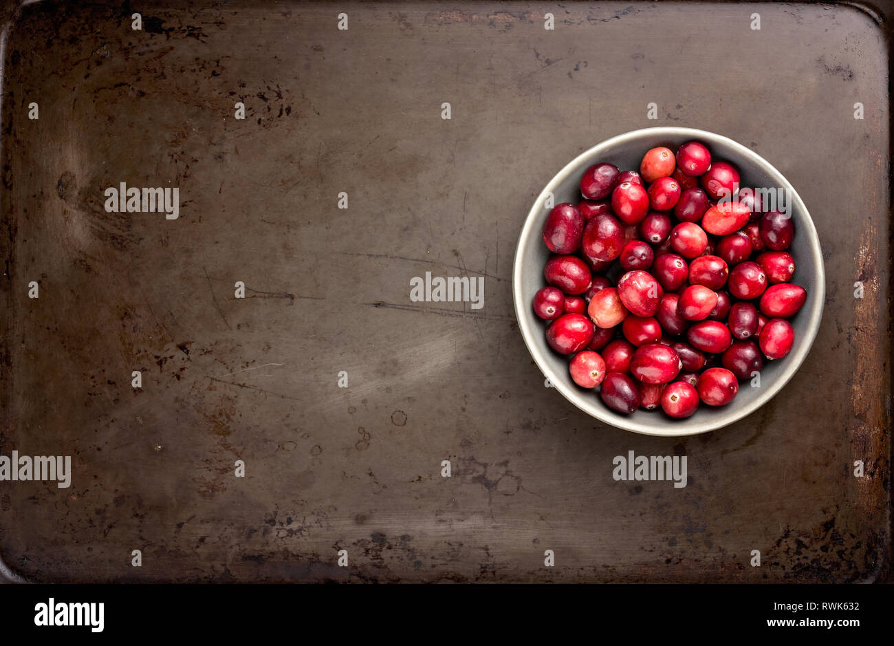 https://c8.alamy.com/comp/RWK632/bowl-of-rustic-fresh-cranberries-on-an-old-vintage-baking-pan-RWK632.jpg