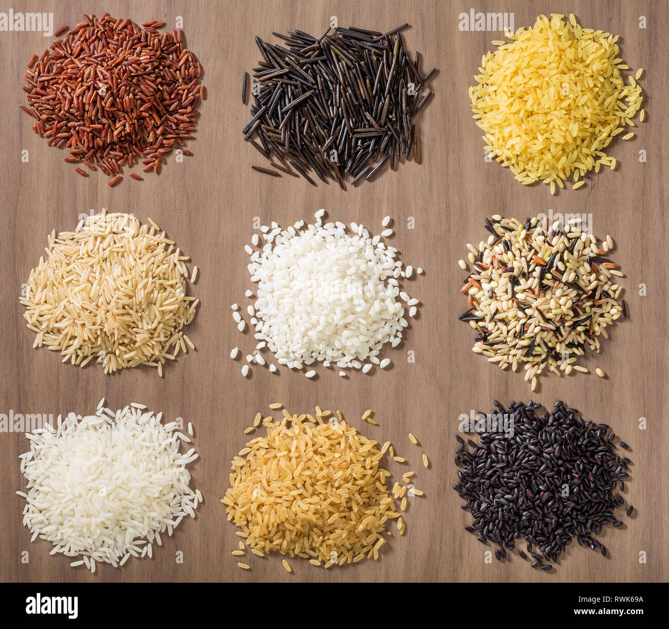 Piles of different rice varieties over a wooden background including