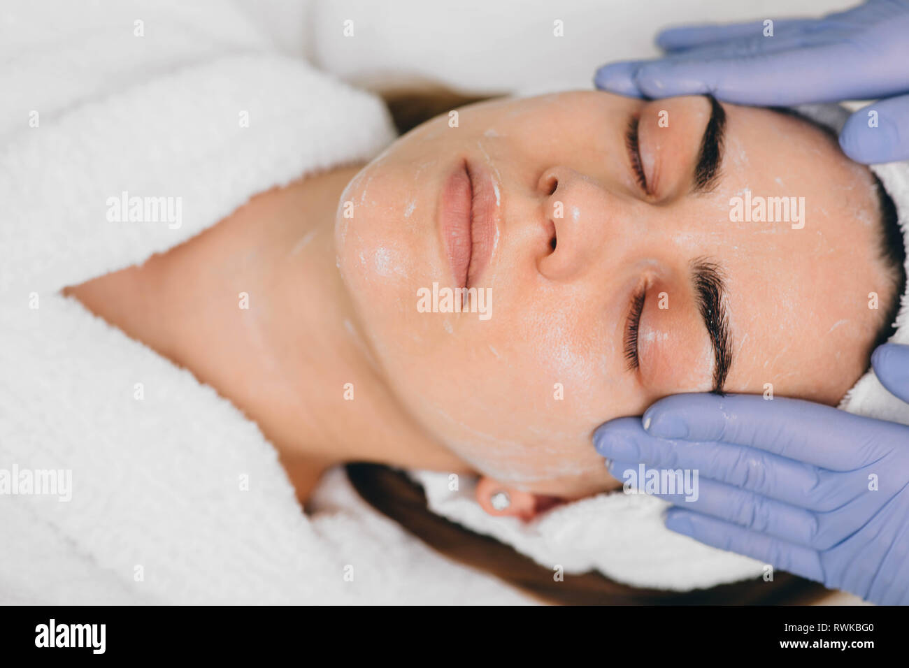 woman receiving facial treatment at beauty salon. Exfoliation Stock Photo