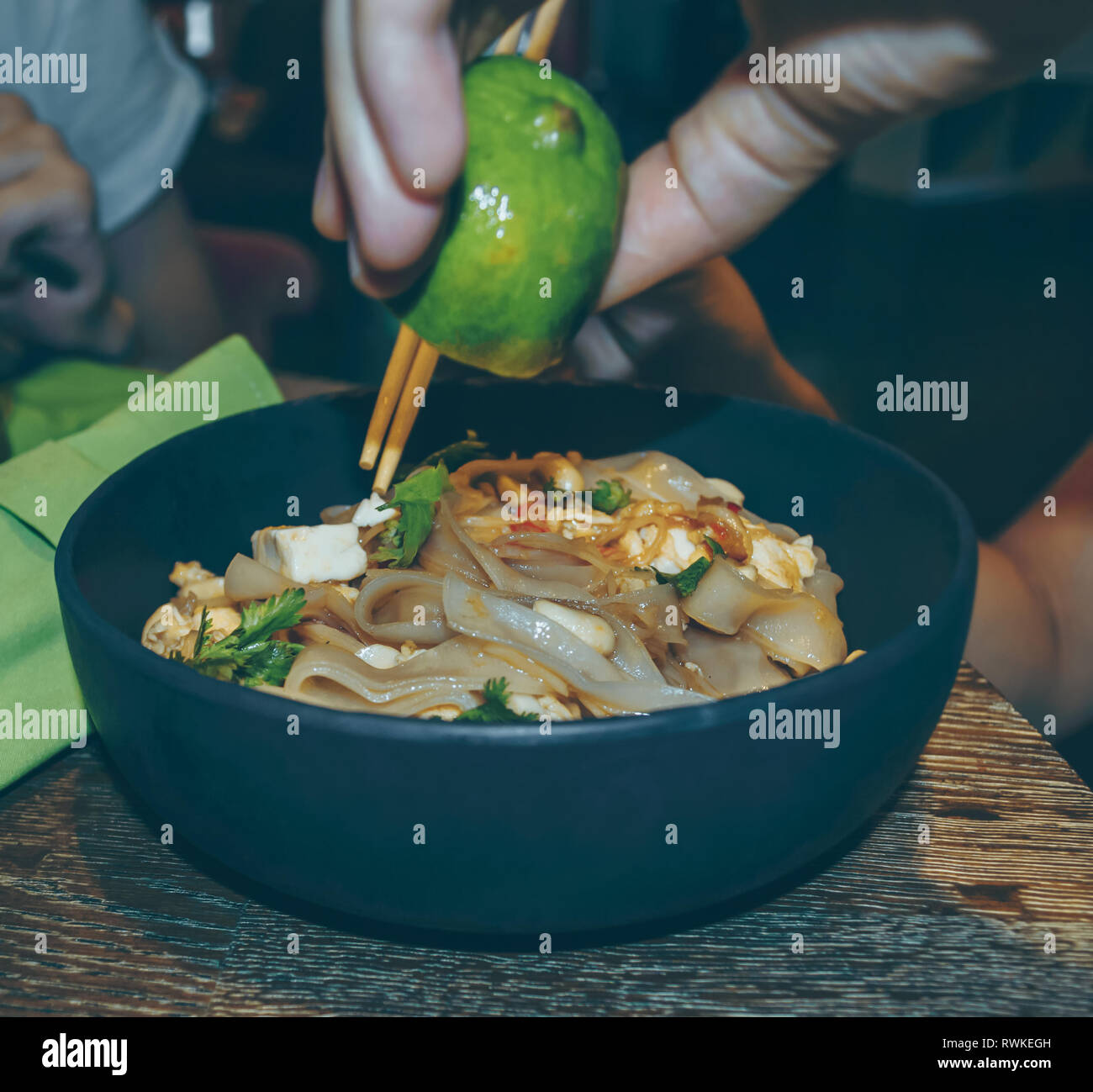 close up view of asian noodles dish being sprinkled with lime Stock Photo