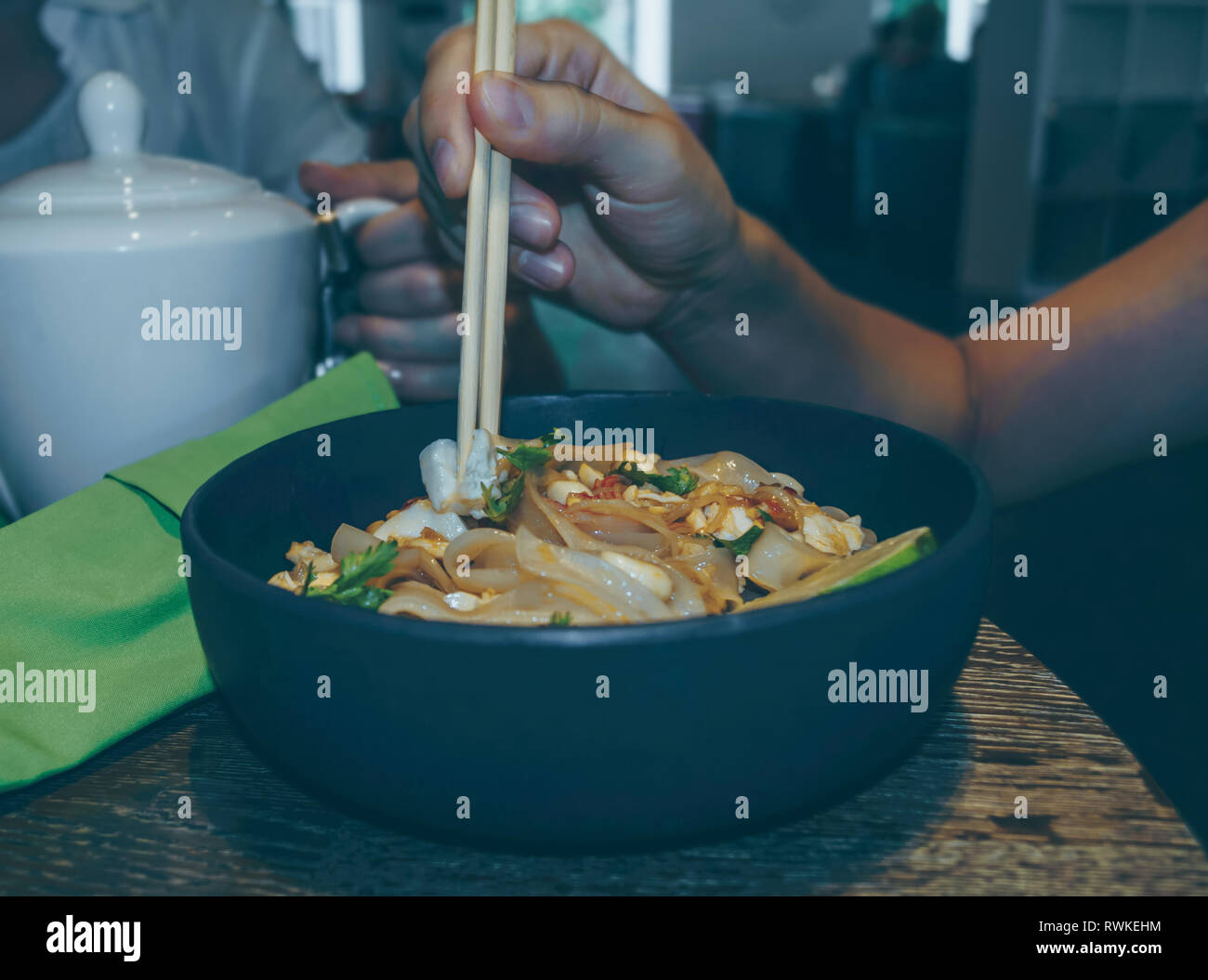 food background of woman holding piece of tofu in her chopsticks Stock Photo