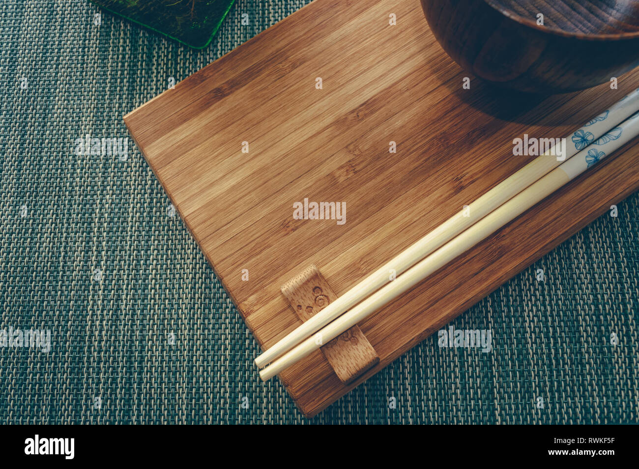 top view of bamboo board with wooden chopsticks and bowl asian style tablewear Stock Photo