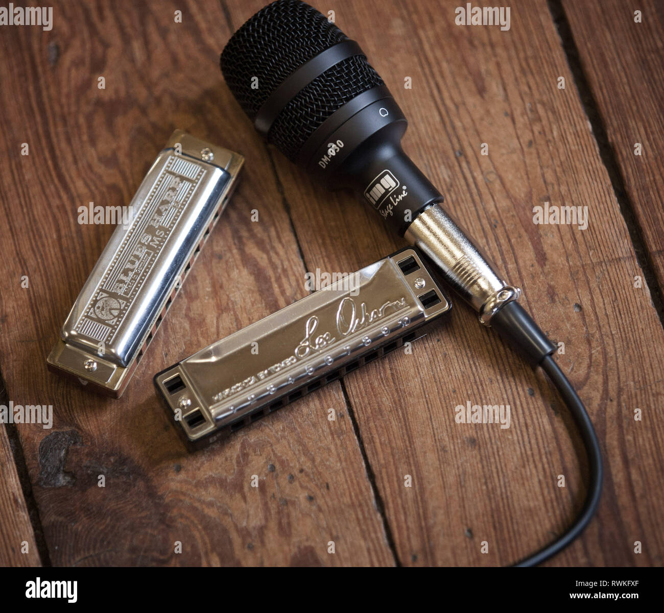 Hohner blues harp harmonica and Lee Oscar harmonica with img microphone on a wooden background. Stock Photo