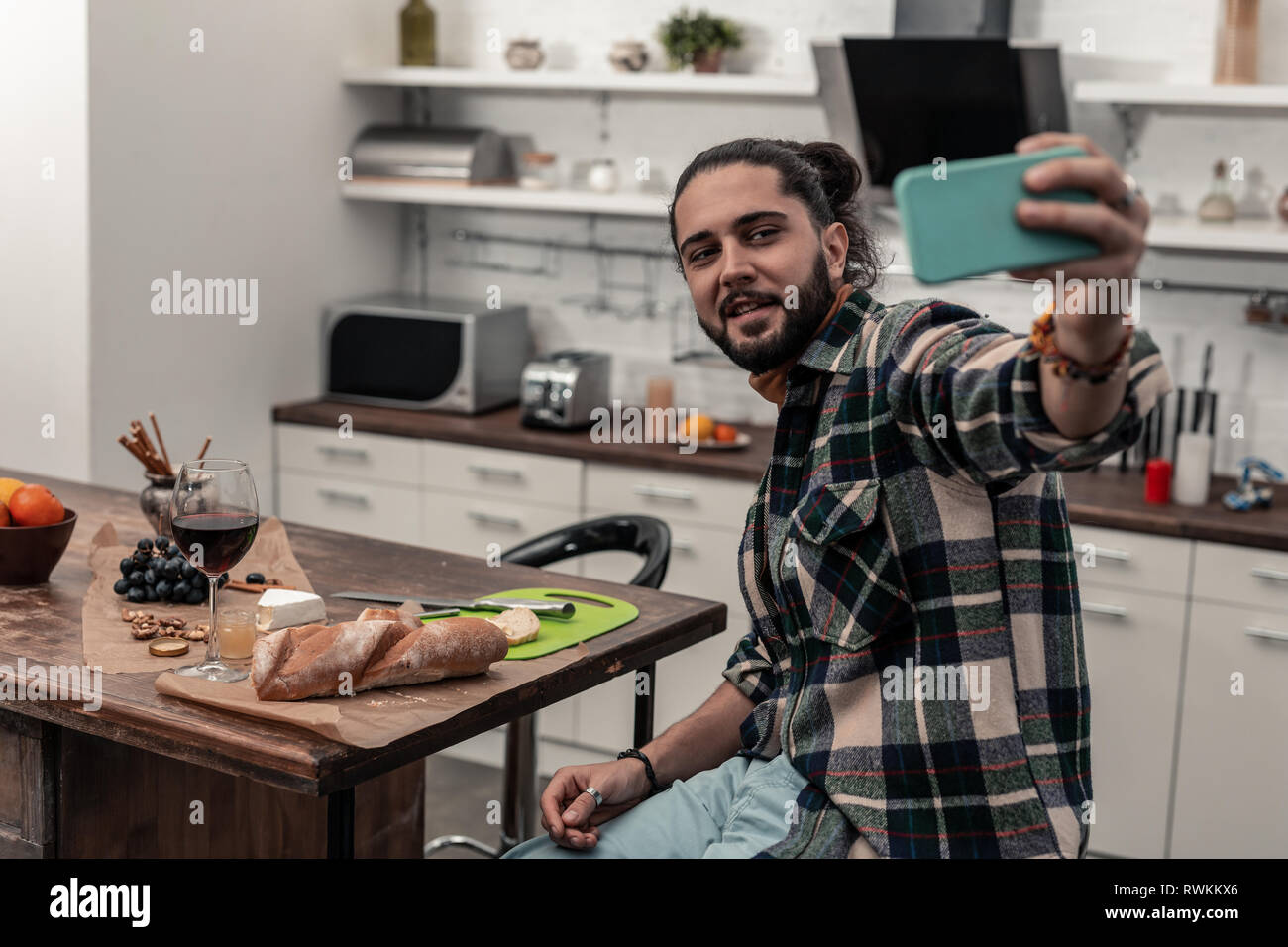 Positive cheerful man taking selfies in the kitchen Stock Photo