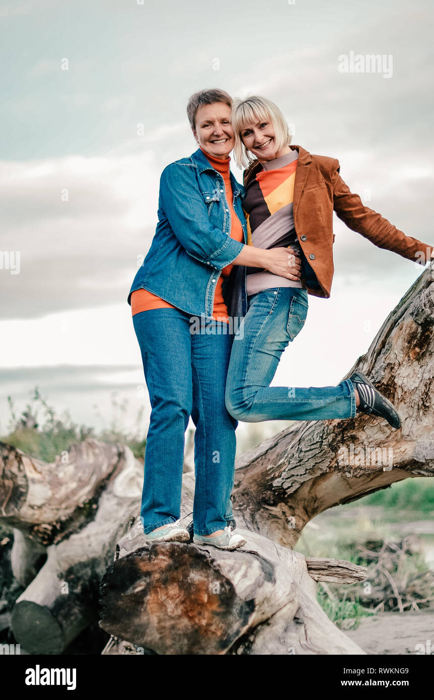 Mature mom and daughter are fooling around on a log. Family, fun weekend outdoors Stock Photo