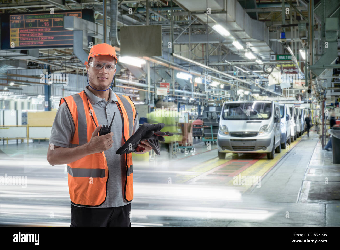 Composite image of car worker using digital tablet on production line in car factory Stock Photo