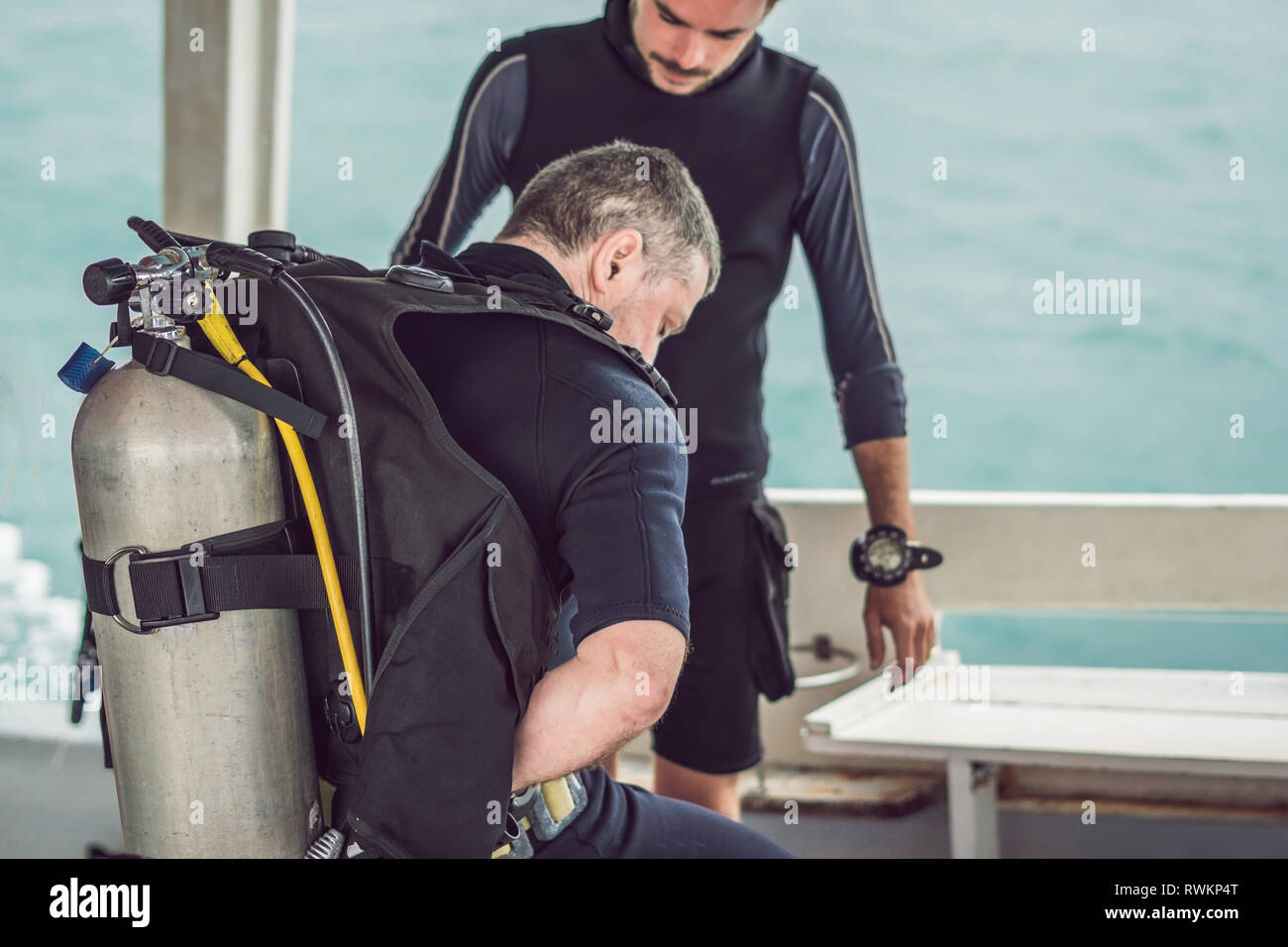 Diving instructor helps a beginner diver prepare for diving Stock Photo