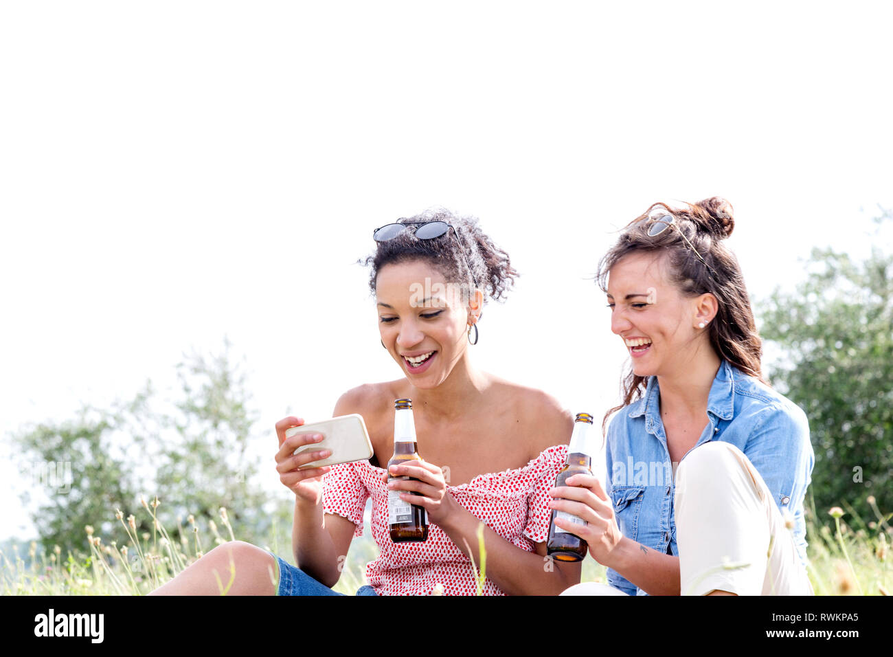 Friends checking mobile phone outdoors Stock Photo