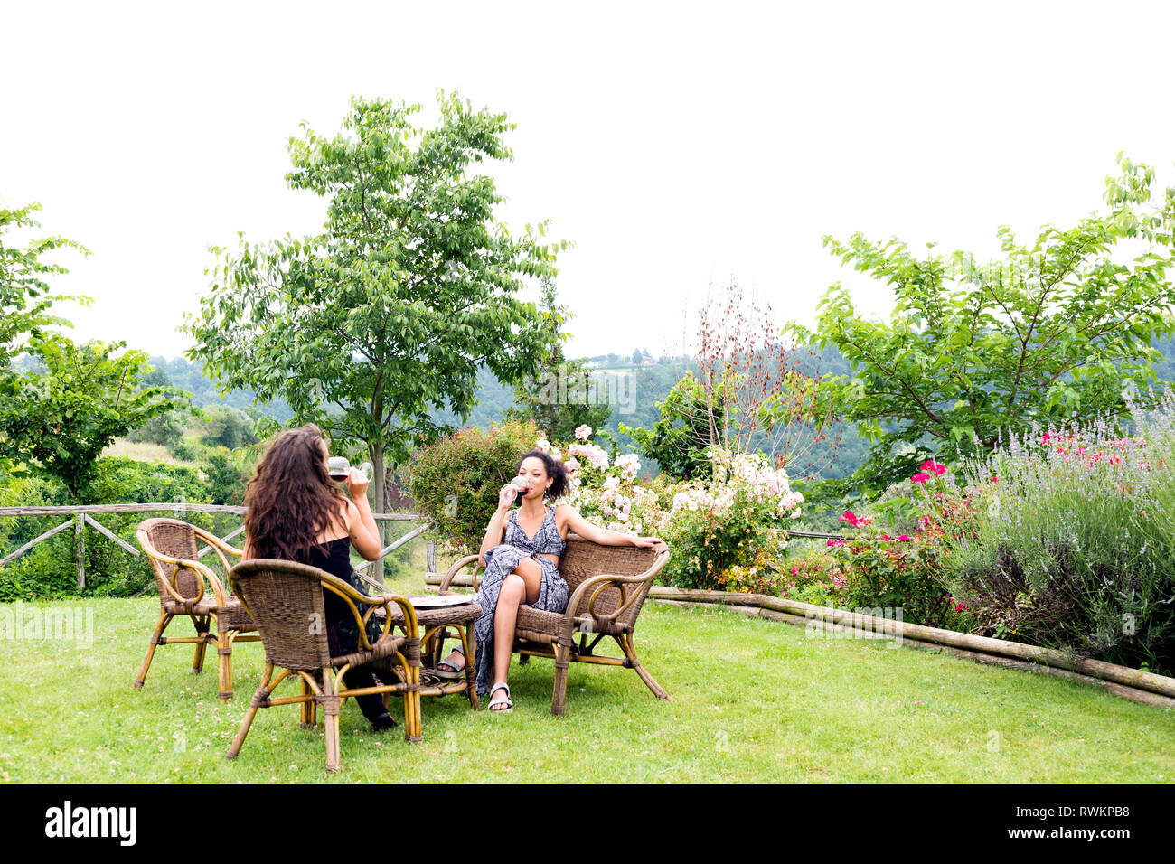 Women on wicker chairs in countryside garden, Città della Pieve, Umbria, Italy Stock Photo