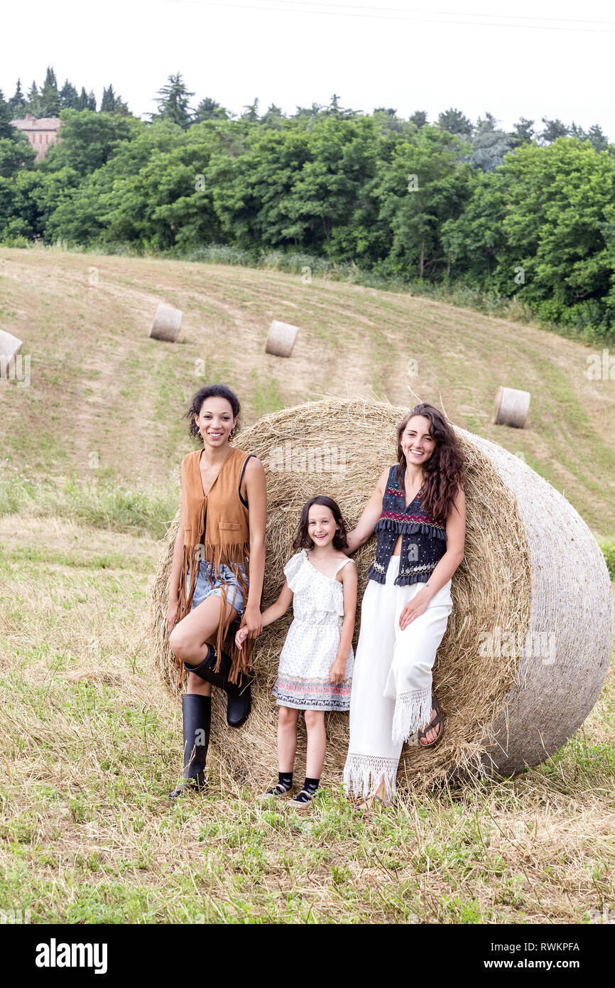 Friends and girl in field of hay bales, Città della Pieve, Umbria, Italy Stock Photo