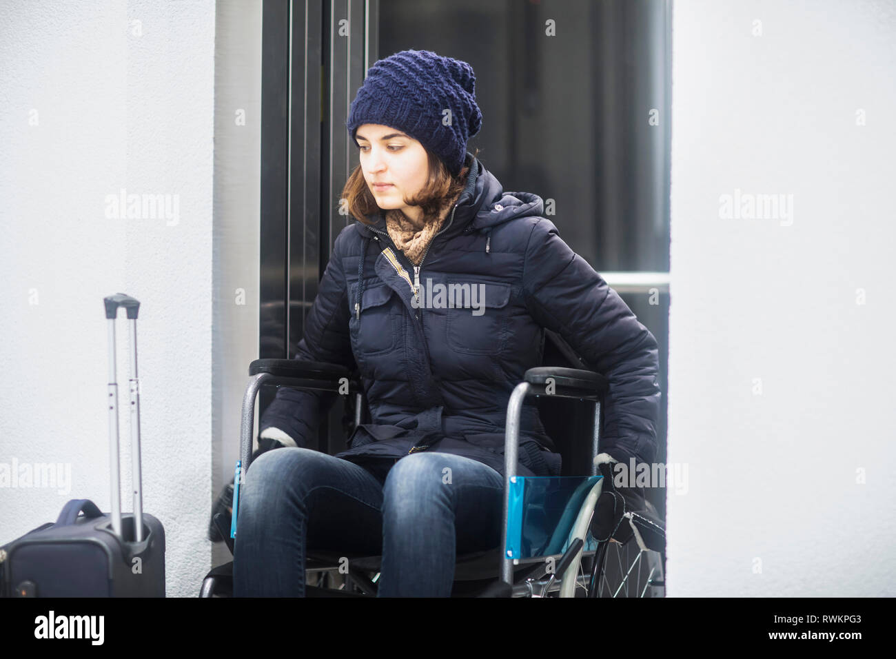Woman in wheelchair with luggage Stock Photo