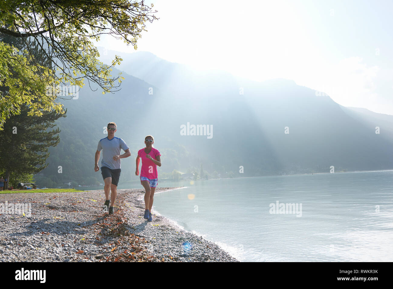 Joggers running by Lac d'Annecy, Annecy, France Stock Photo