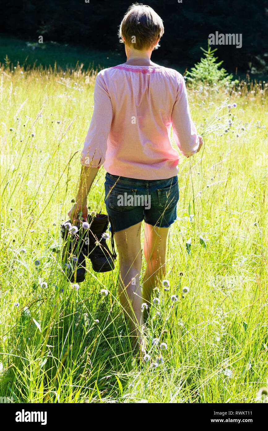 Woman picking wild flowers in forest Stock Photo