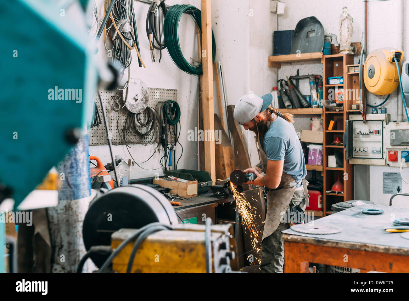 Axe maker using steel grinder in workshop Stock Photo