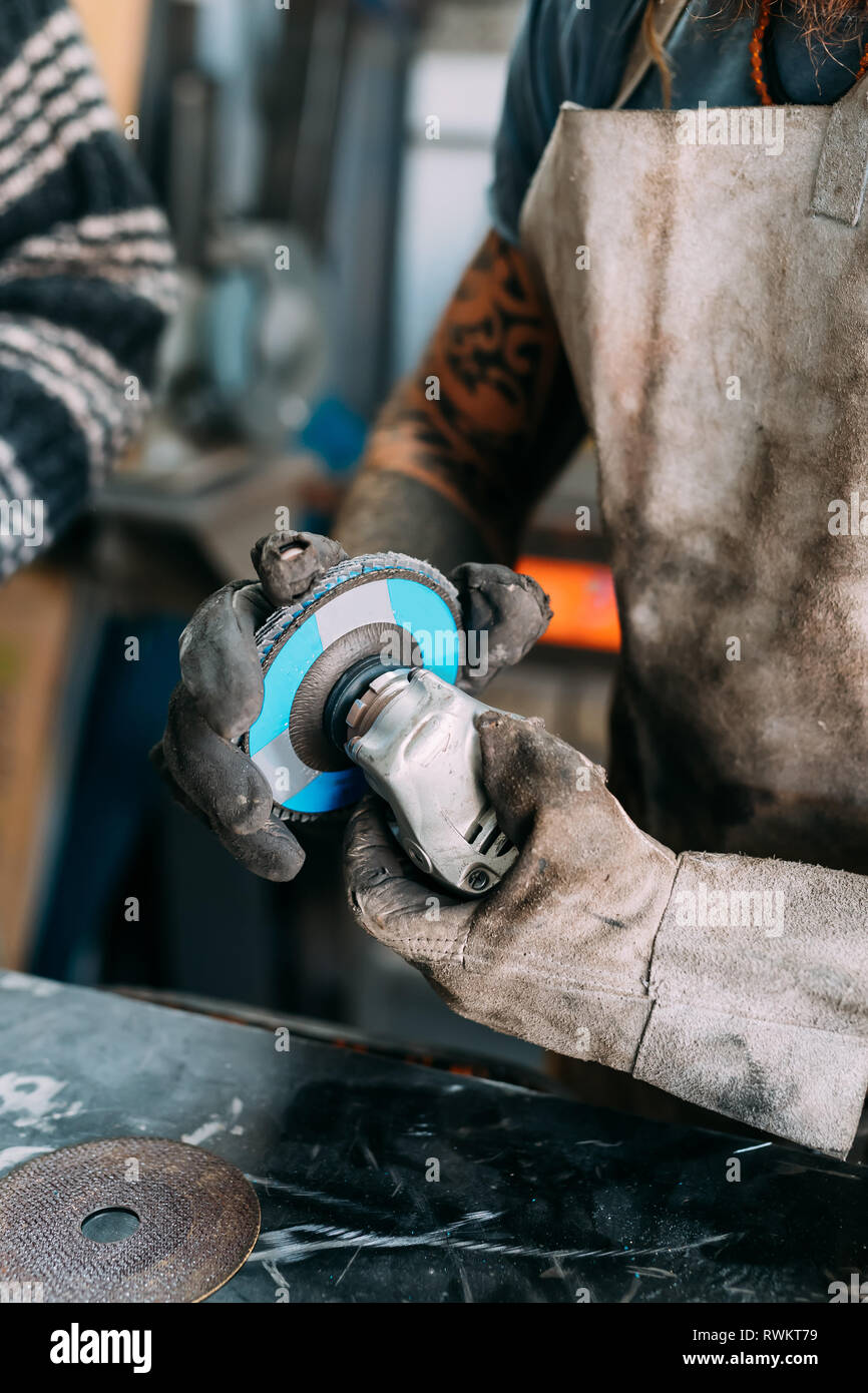Axe maker using steel grinder in workshop Stock Photo
