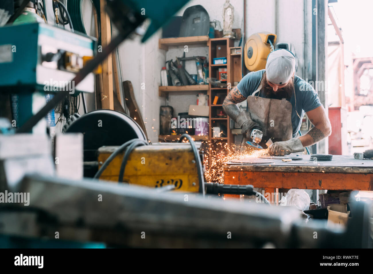 Axe maker using steel grinder in workshop Stock Photo
