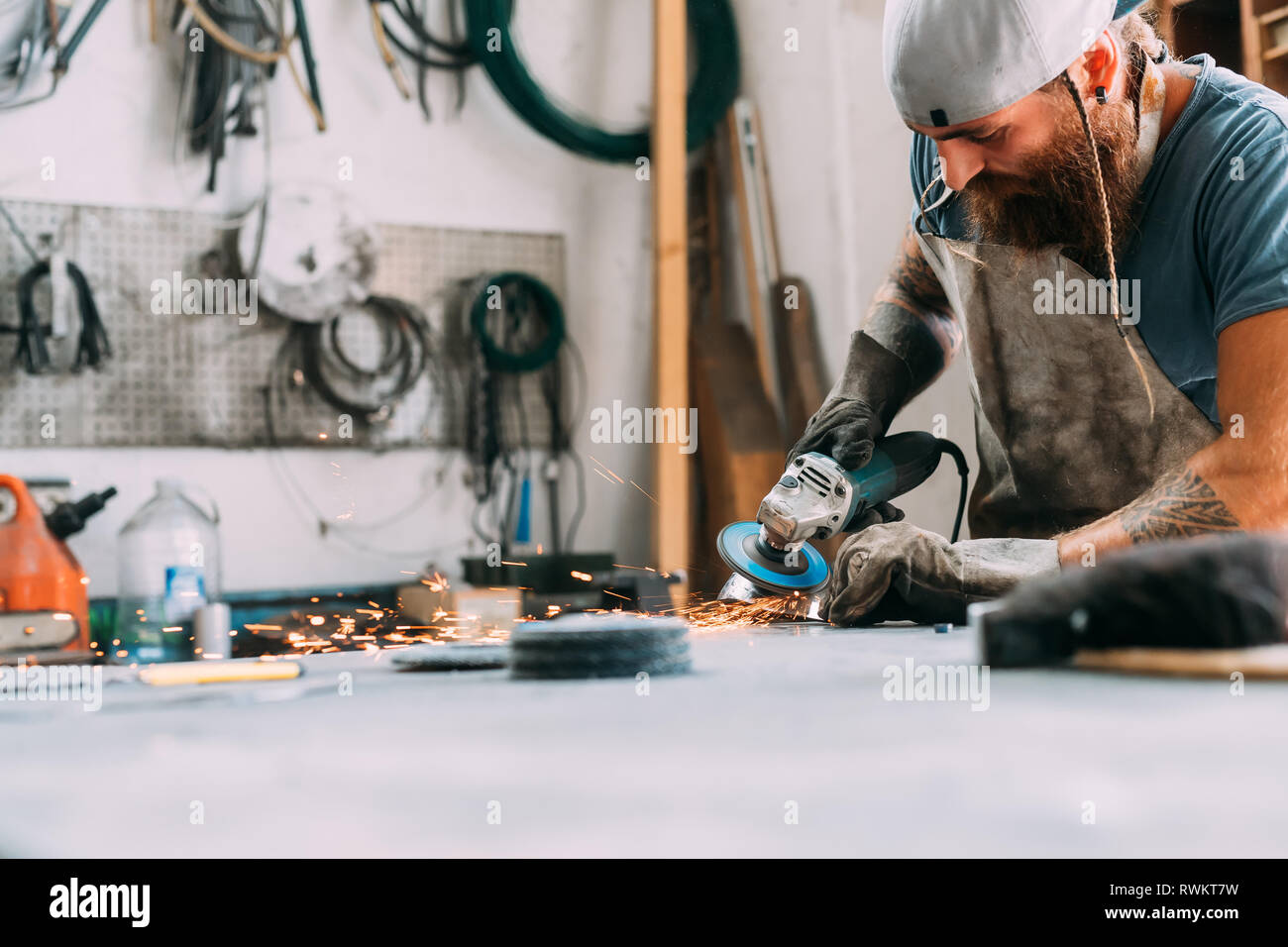 Axe maker using steel grinder in workshop Stock Photo