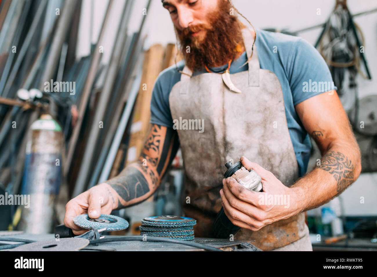 Axe maker using steel grinder in workshop Stock Photo