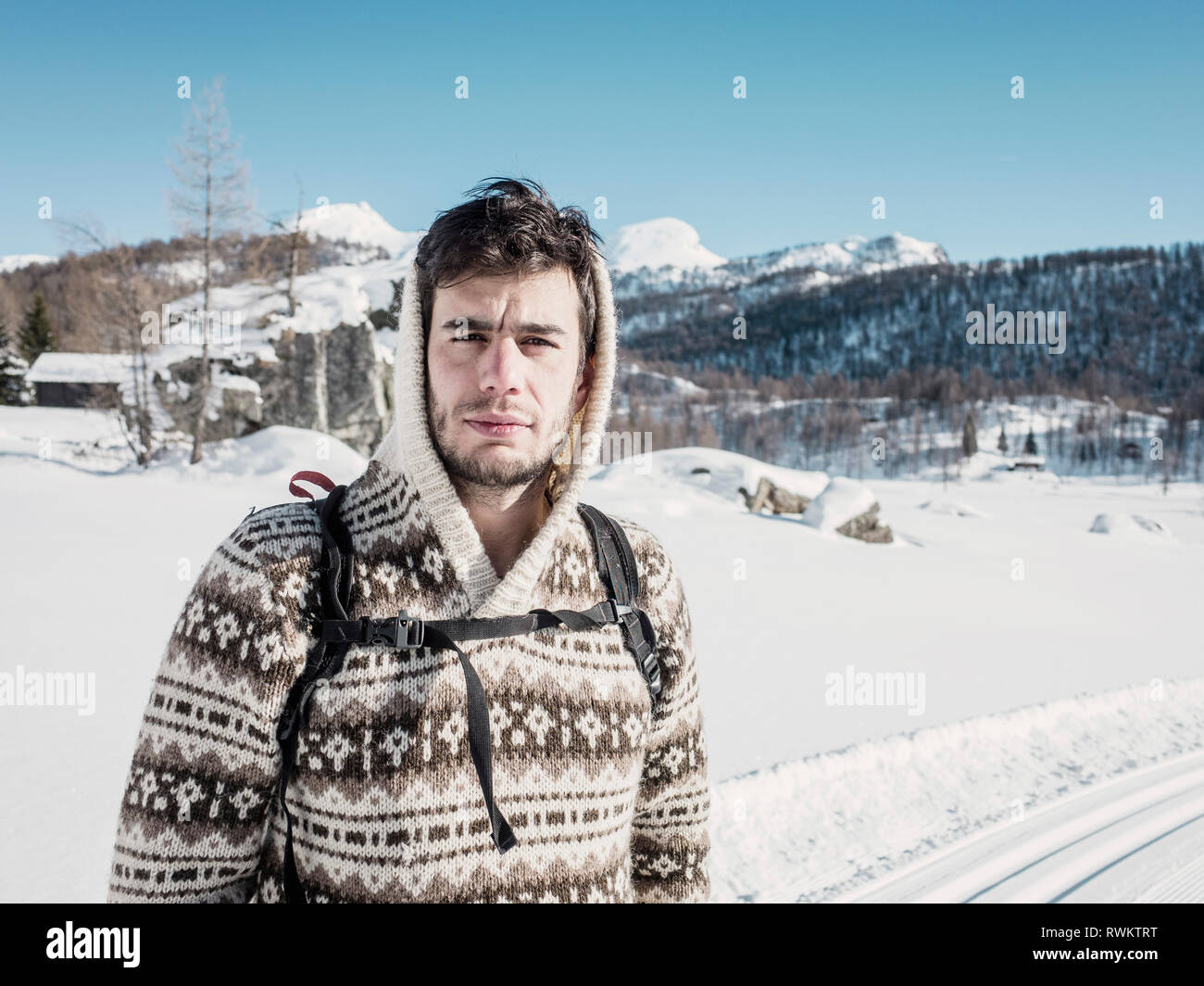 Mid adult man in hooded sweater in snow covered mountain landscape, portrait, Alpe Ciamporino, Piemonte, Italy Stock Photo