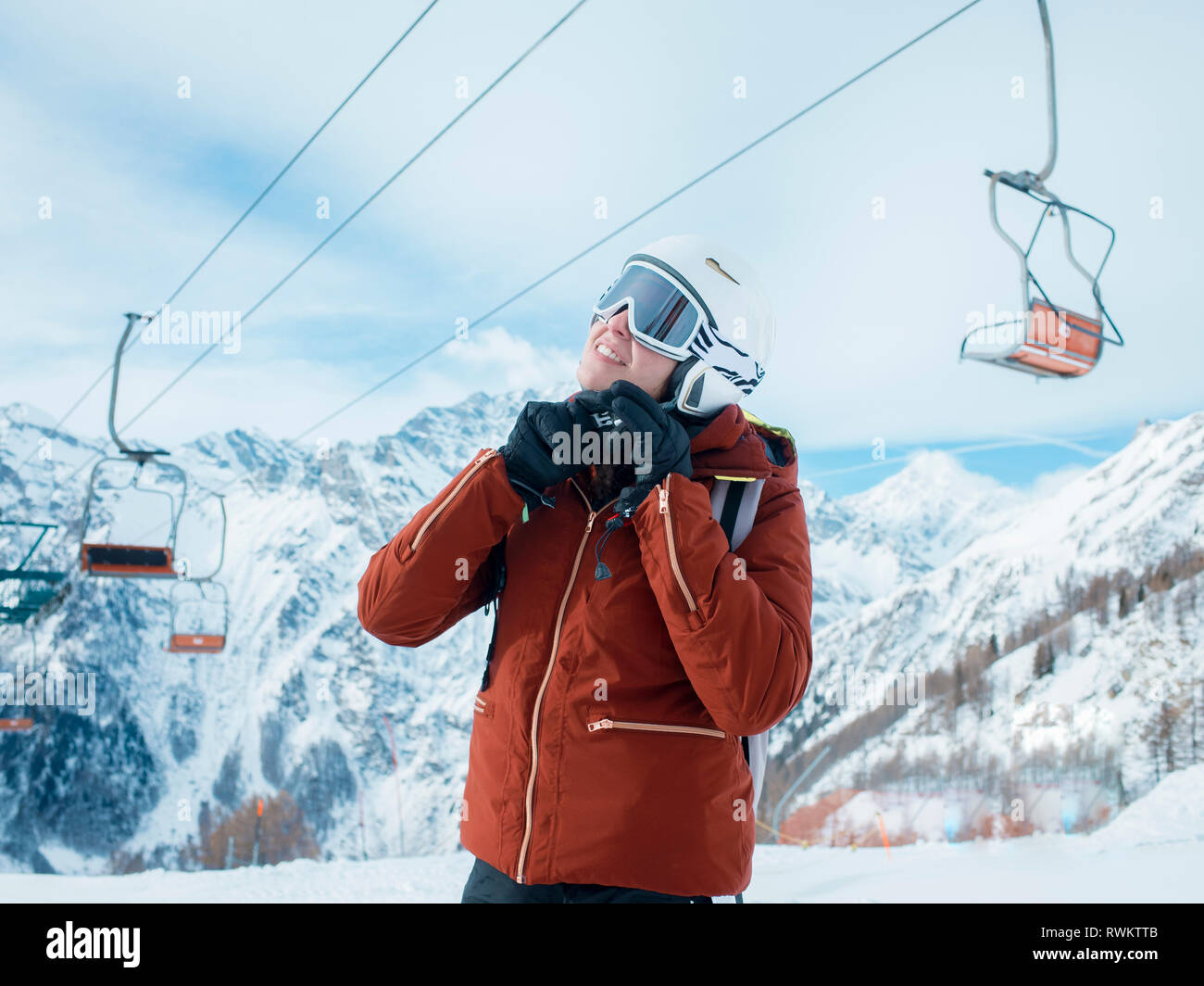 Young woman skier fastening helmet in snow covered landscape, Alpe Ciamporino, Piemonte, Italy Stock Photo