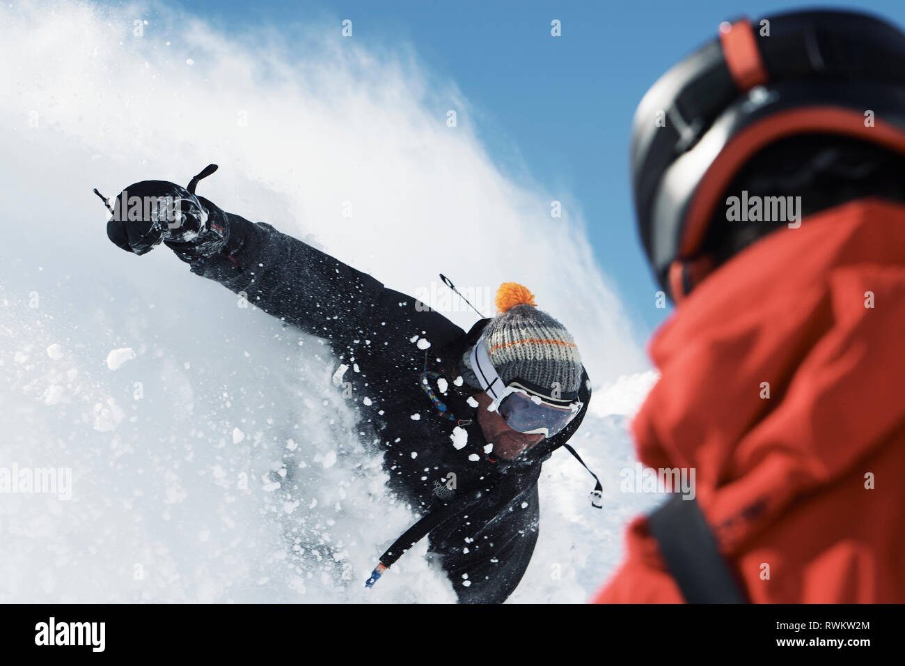 Male snowboarder speeding down mountainside, over shoulder view, Alpe-d'Huez, Rhone-Alpes, France Stock Photo