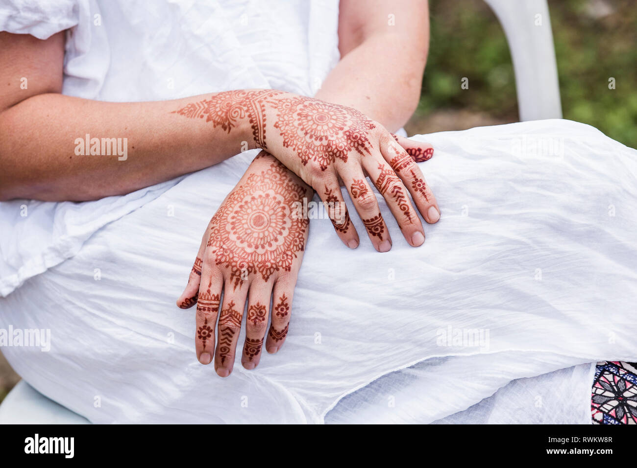 Woman in white dress with henna tattoo on hands Stock Photo