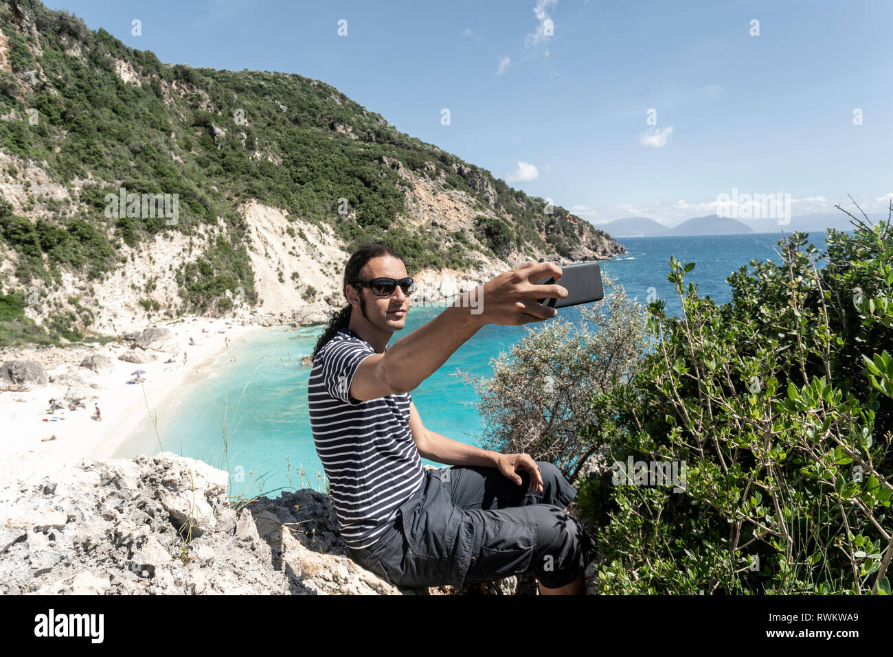 Man taking selfie on cliff top, Lefkada Island, Levkas, Greece Stock Photo