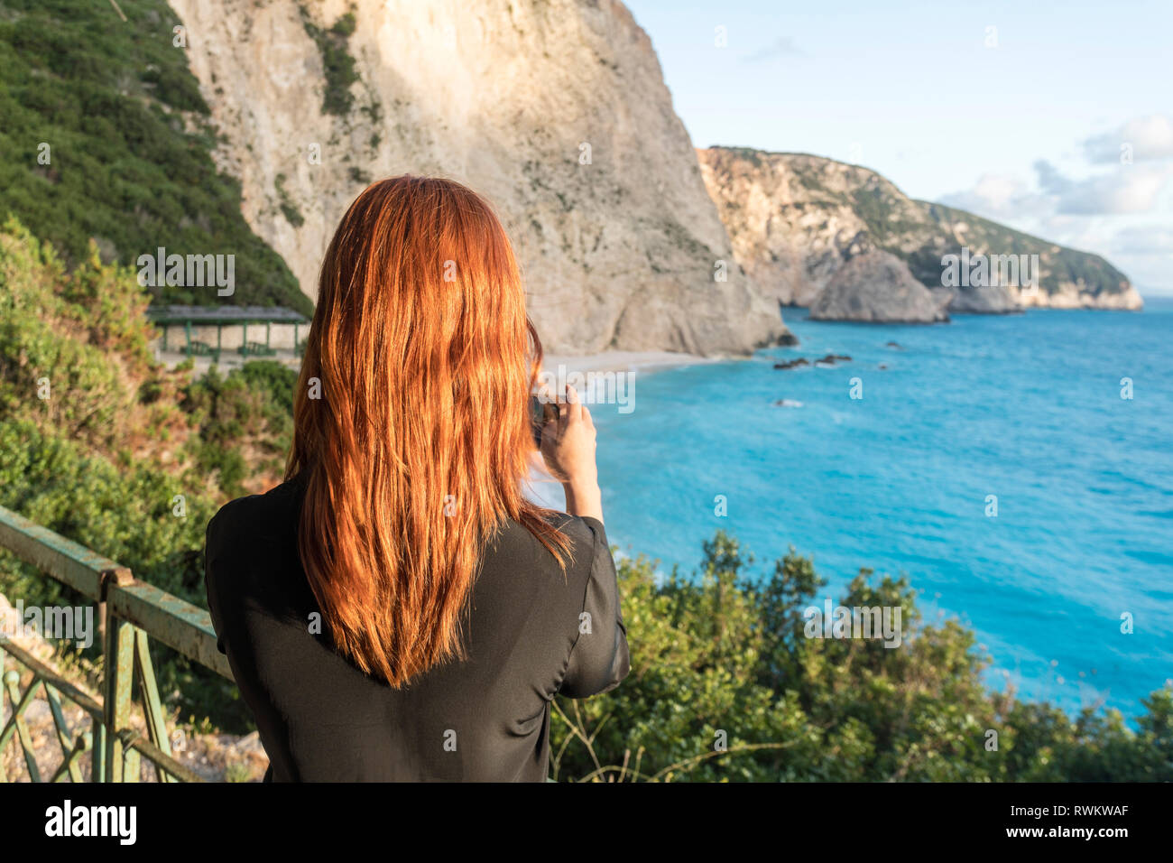 Woman taking photograph of turquoise sea, Lefkada Island, Levkas, Greece Stock Photo