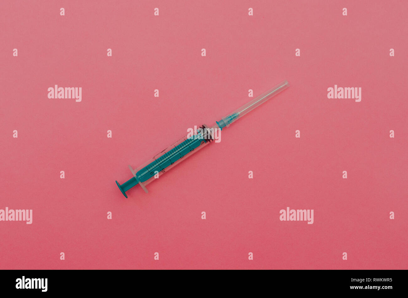 Syringe with green piston on a pink background. The concept of health Stock Photo